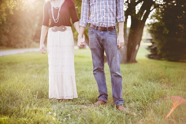 一对情侣手牵着手在草地上拍了一张特写照片 他们头顶上闪烁着阳光 — 图库照片