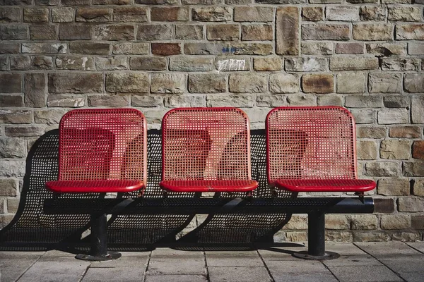 Belo tiro de três assentos vermelhos na estação de ônibus de uma área urbana — Fotografia de Stock