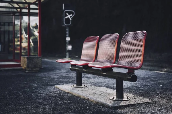 Belle prise de vue de trois sièges rouges dans la gare routière d'une zone urbaine — Photo