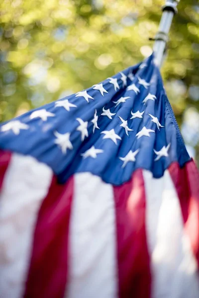 Vertikal låg vinkel skott av USA flaggan hängande från en pol med en suddig bakgrund — Stockfoto
