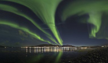 A breathtaking shot of wind of colors reflecting in the sea making it look like a fairytale scene in Lofoten, Norway clipart