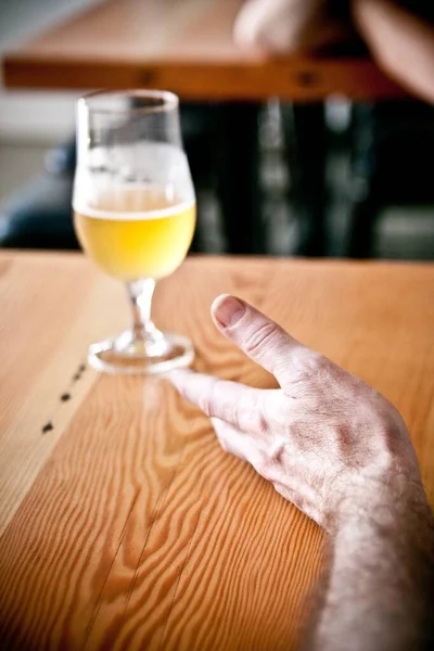 Vertikal bild av ett glas öl och en mänsklig hand på bordet - fredag kväll koncept — Stockfoto