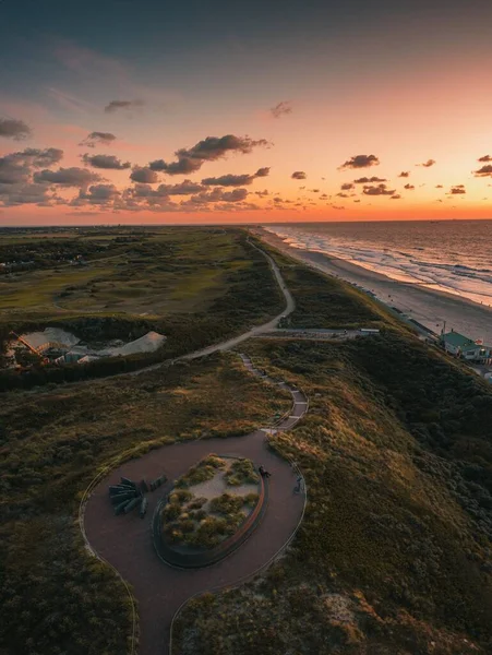 Pionowe ujęcie pod wysokim kątem zielonej plaży i falistego oceanu o zachodzie słońca w Domburg, Holandia — Zdjęcie stockowe