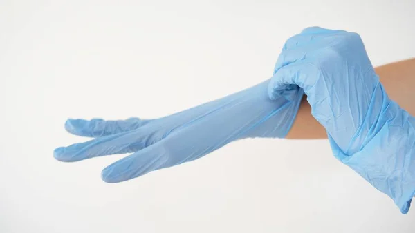 Schöne Aufnahme einer Person, die blaue Gummihandschuhe an der Hand auf weißem Hintergrund anzieht — Stockfoto