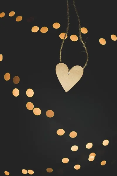 Vertikální detailní záběr vyříznutého řetězce ve tvaru srdce s rozmazanými světly na pozadí — Stock fotografie