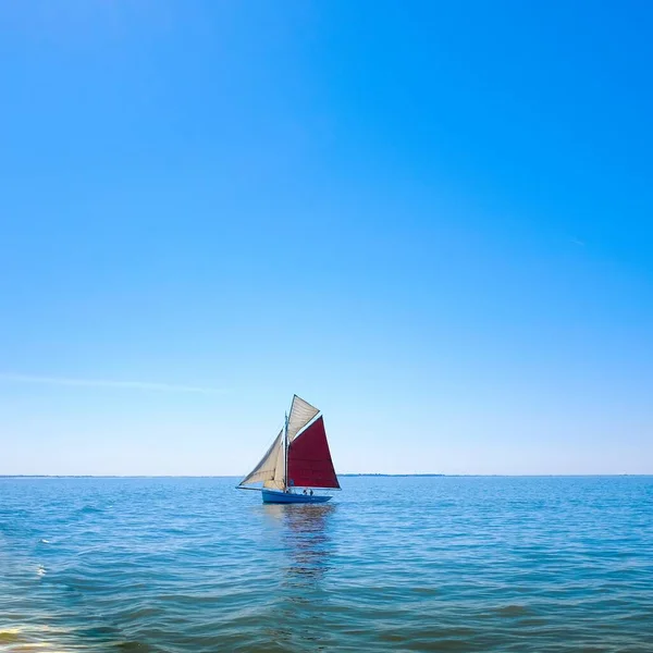 Красно-белая лодка, плывущая посреди моря под чистым небом — стоковое фото