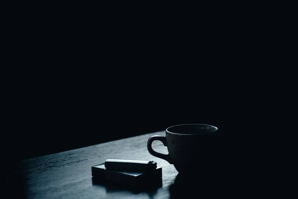 Una taza de café junto a un paquete de cigarrillos y un encendedor — Foto de Stock