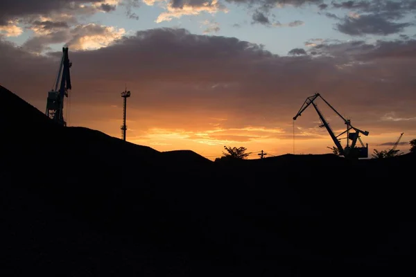 Krásný záběr jeřábů pracujících během západu slunce symbolizující rušný průmyslový život — Stock fotografie
