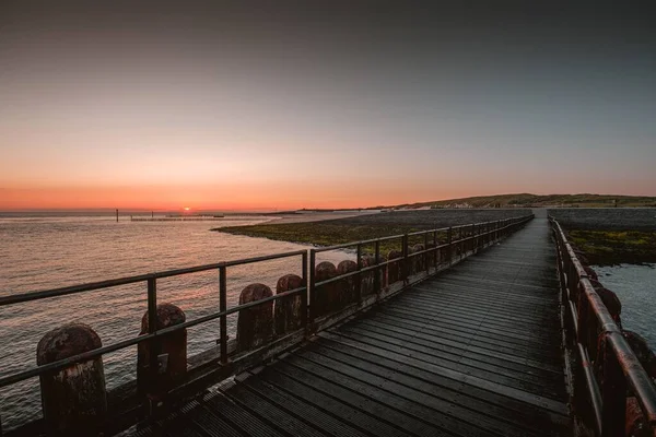 Cais de madeira à beira-mar sob o belo pôr-do-sol em Westkapelle, Países Baixos — Fotografia de Stock