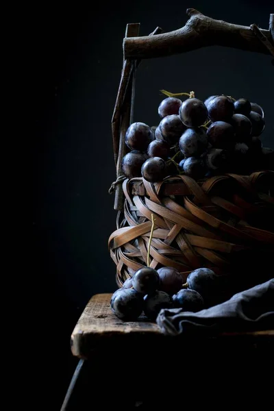 Vertikale Nahaufnahme von Weinbeeren in einem Korb auf schwarzem Hintergrund — Stockfoto
