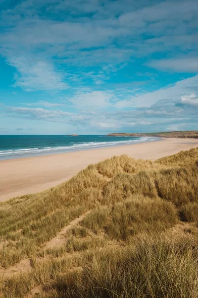 Vertical shot of the grass covered beach by the calm ocean captured in Cornwall, England — Stock Photo, Image