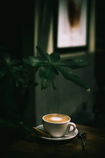 Pionowe ujęcie filiżanki kawy na drewnianym stole — Zdjęcie stockowe