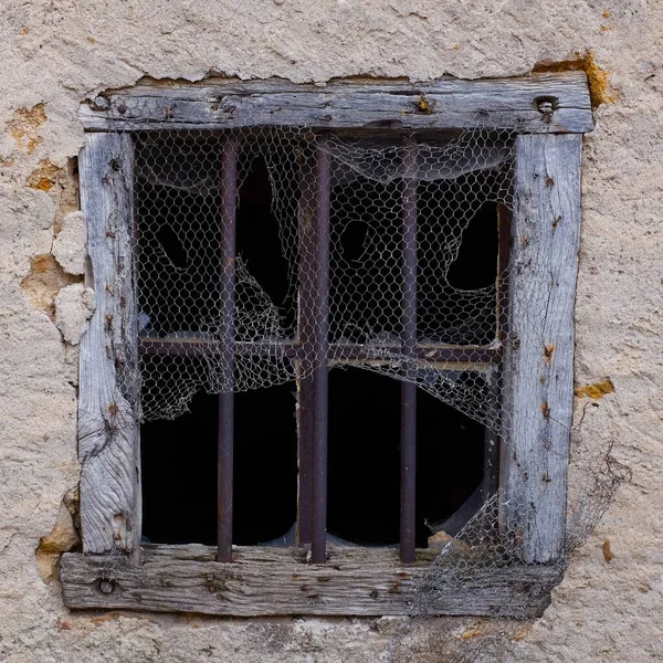 Gros plan d'une vieille fenêtre cassée recouverte d'un filet percé de trous — Photo