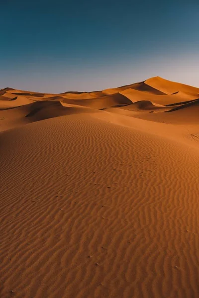 Tiro vertical de un desierto pacífico bajo el cielo azul claro capturado en Marruecos — Foto de Stock