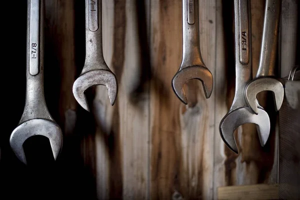 Closeup shot of different sized wrenches hanging with a wooden wall in the background — Stock Photo, Image