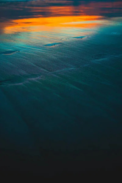 Vertikale Aufnahme der Reflexion des Sonnenuntergangs auf dem nassen Sand des Strandes, aufgenommen in bali — Stockfoto