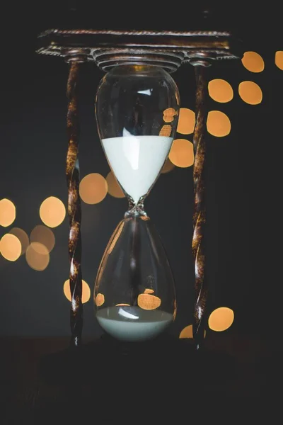 Gros plan vertical d'une horloge en verre de sable avec des lumières floues en arrière-plan — Photo