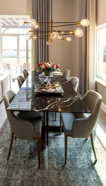 Tiro vertical de uma mesa de jantar sob um belo lustre em um quarto luxuoso — Fotografia de Stock