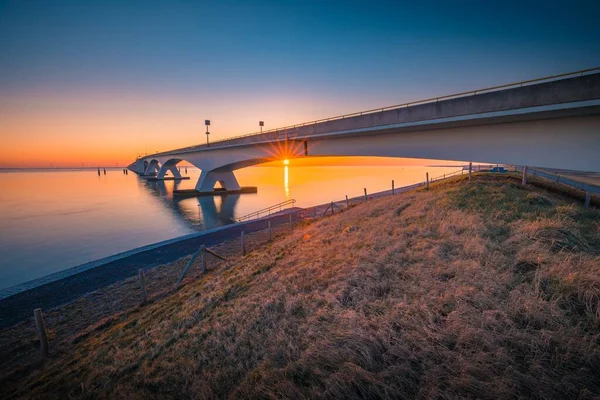 在荷兰Zeelandbridge拍摄的日落时分，一座横跨平静河流的桥的美丽景色 — 图库照片