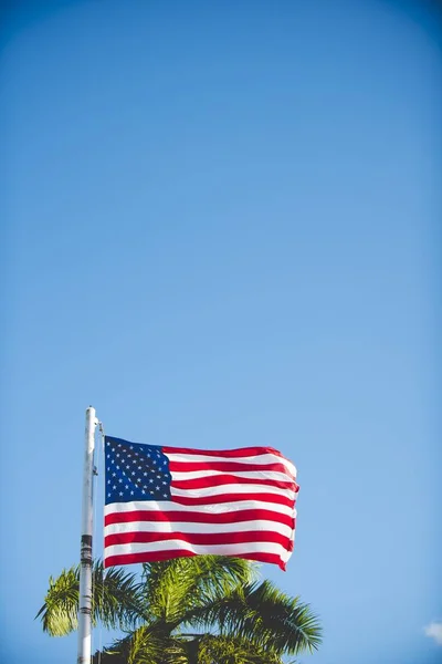 Gambar vertikal bendera Amerika Serikat pada tiang dengan langit biru di latar belakang — Stok Foto