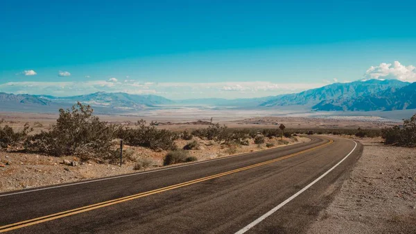 Estrada que atravessa o deserto com as montanhas ao fundo capturadas na Califórnia — Fotografia de Stock