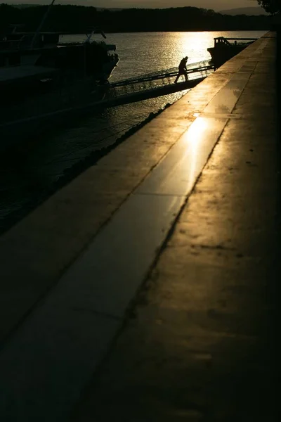 Scatto verticale di una persona che lascia la nave e il tramonto che si riflette nel mare sullo sfondo — Foto Stock