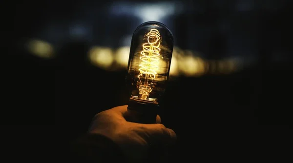 Крупный план человеческой руки, держащей лампу на размытом фоне — стоковое фото