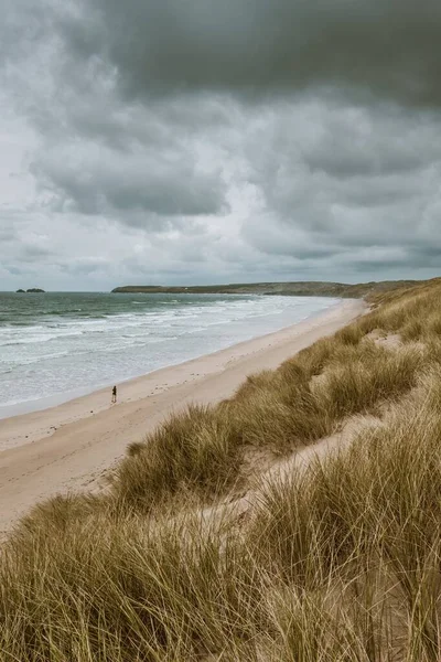 Vertical shot of the grass covered beach by the calm ocean captured in Cornwall, England — Stock Photo, Image