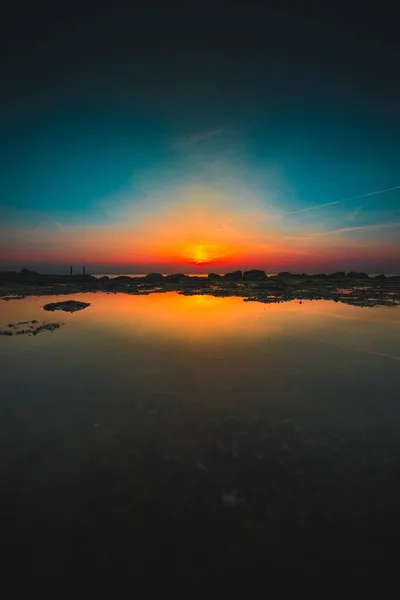 Vertikale Aufnahme der Reflexion des Sonnenaufgangs am Strand, aufgenommen in Westkapelle, Niederlande — Stockfoto