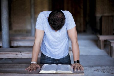 Closeup shot of a male reading the bible on a wooden table with a blurred background clipart