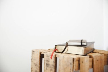Closeup shot of a bible and notepad on a wooden box with a white background clipart