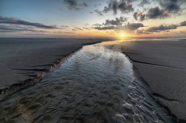 Bela paisagem do pôr do sol refletida em um lamaçal sob o céu nublado — Fotografia de Stock