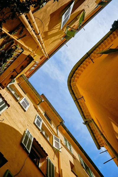 Вертикальный низкоугольный снимок зданий под голубым небом, снятый в Ментоне, Французская Ривьера, Франция — стоковое фото