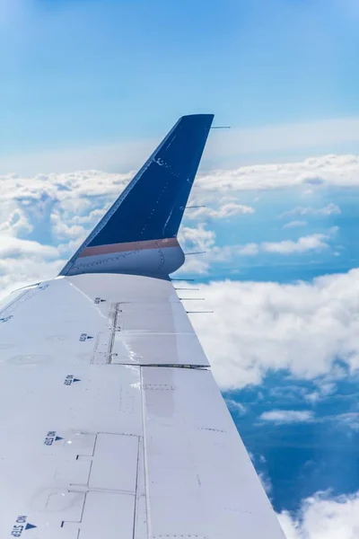 Κάθετη κοντινή λήψη μιας πτέρυγας αεροπλάνου με τα όμορφα σύννεφα στο φόντο — Φωτογραφία Αρχείου