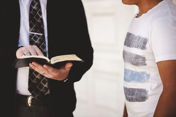 Close-up tiro de um macho apontando uma sentença na bíblia com um fundo borrado — Fotografia de Stock
