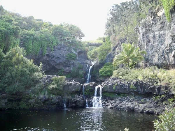 Beautiful view of a waterfall pouring in the middle of mountainous scenery in Hawaii — Stock Photo, Image