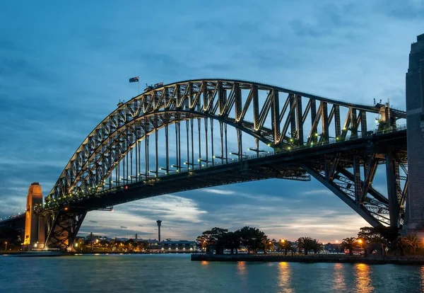 Sydney Harbour Bridge with a lot of lights reflected in the sea under the breathtaking sky — Stock Photo, Image