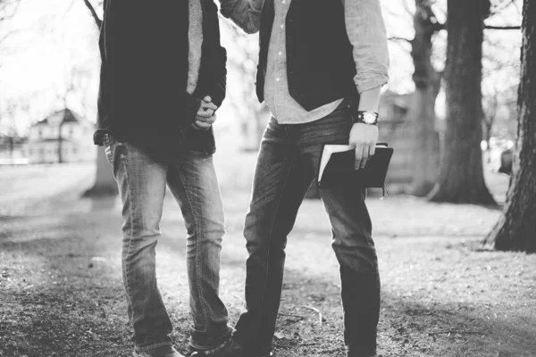 Grayscale shot of two males talking to each other while holding the bible with blurred background — Stock Photo, Image