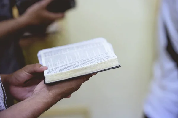 Primo piano di una persona che legge la Bibbia con uno sfondo sfocato — Foto Stock