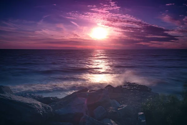 Lélegzetelállító naplemente ég felett élénk lila felhők tükröződnek a tengerben — Stock Fotó