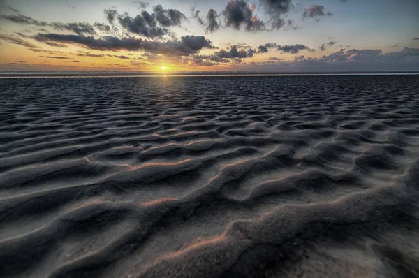Beautiful scenery of the sunset reflected in a mudflat under the cloudy sky — Stock Photo, Image