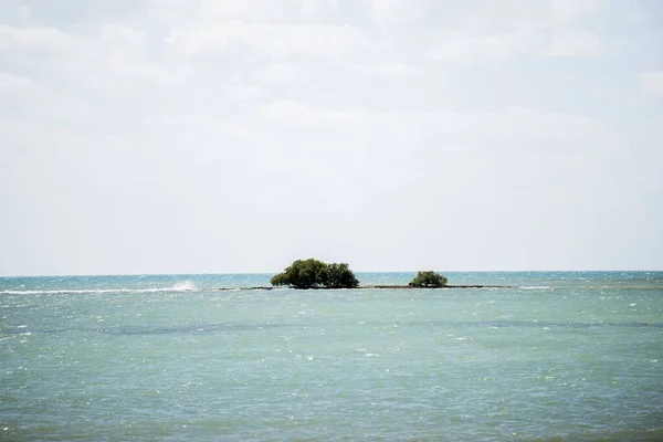 Снимок моря с маленьким островом вдали под облачным небом — стоковое фото