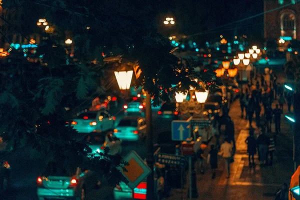 Высокоугольный снимок города ночью с большим количеством людей и транспорта возле уличных фонарей — стоковое фото