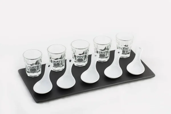 Черный керамический поднос с пятью чашками виски и ложками в форме пластин изолированы на белом фоне — стоковое фото