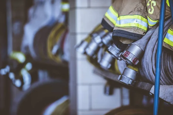 Närbild skott av brandmän kläder och slang med en suddig bakgrund — Stockfoto