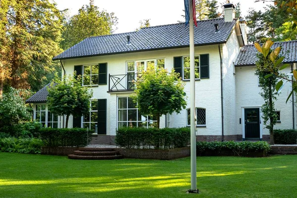 Hermosa casa blanca con un jardín verde rodeado de muchos árboles verdes —  Fotos de Stock