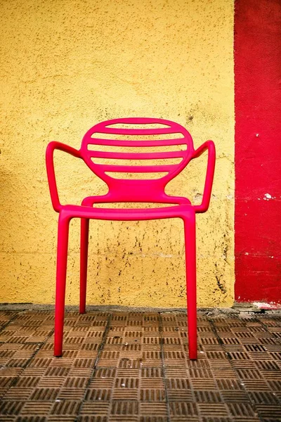 Fransız Rivierası, Menton 'da yakalanan sarı ve kırmızı bir duvarın önündeki kırmızı sandalyenin dikey görüntüsü. — Stok fotoğraf