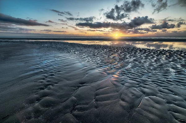 Wunderschöne Landschaft des Sonnenuntergangs, die sich im Watt unter dem bewölkten Himmel widerspiegelt — Stockfoto