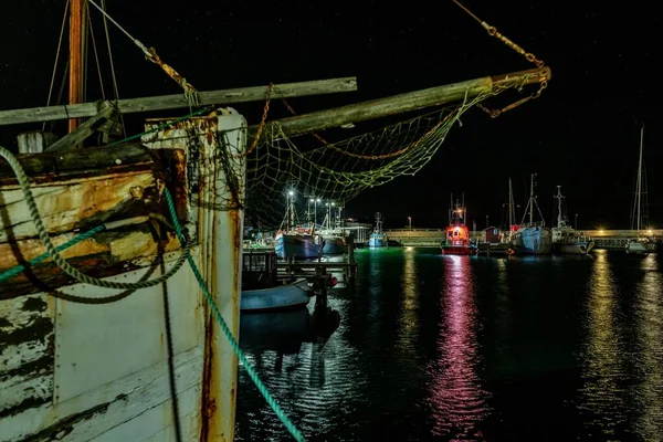 Geceleyin ele geçirilen bir liman tarafından denizdeki ışık ve teknelerin yansıması — Stok fotoğraf