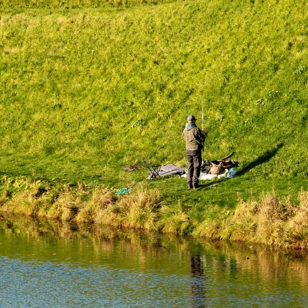 Fisherman on the fields covered with grass by the river captured at day time — Stock Photo, Image